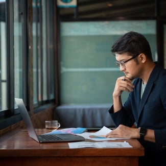 Asian young businessman working with laptop at office, office worker browsing in laptop for necessary information.